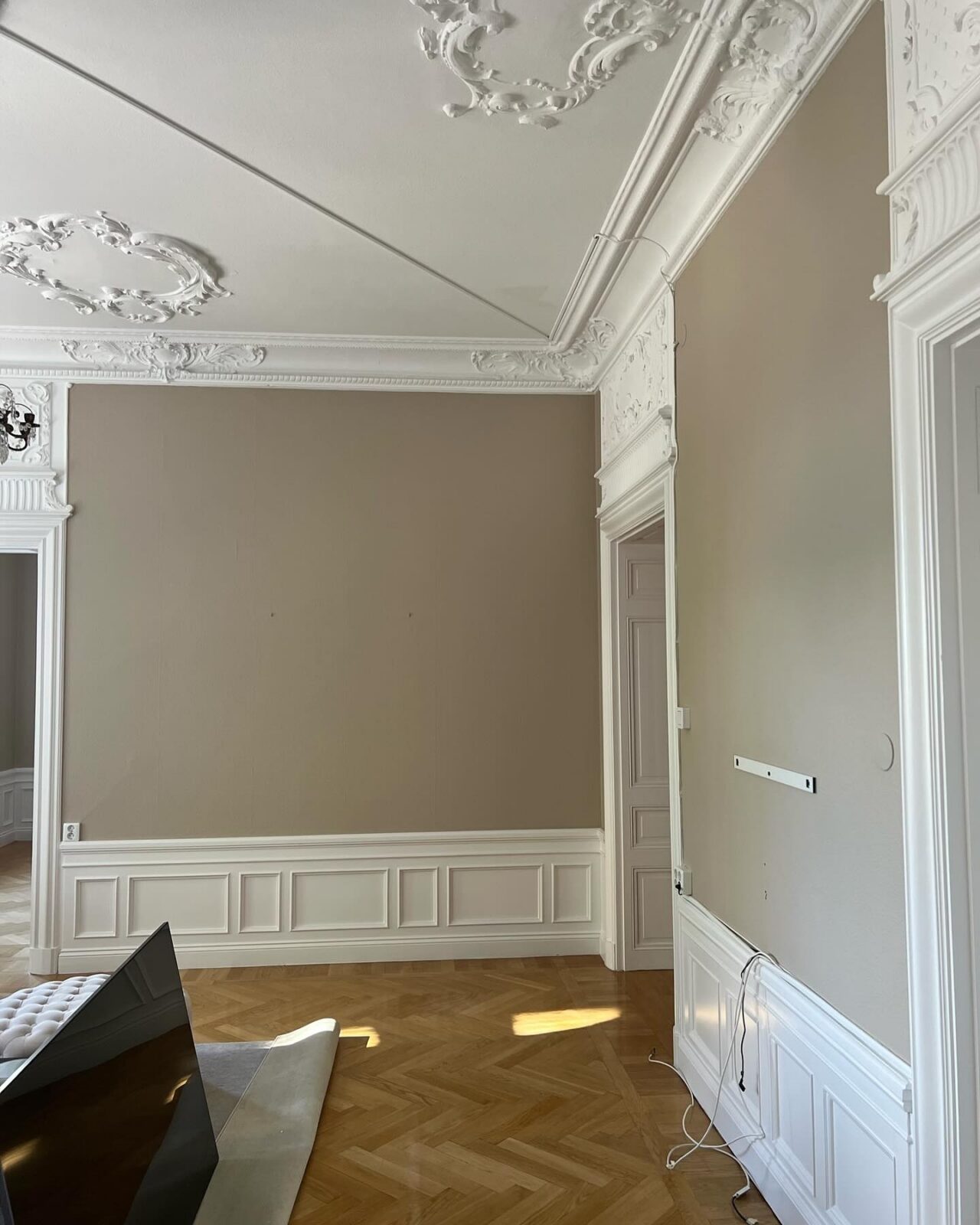Rum med takstuckatur, beige väggar och vit bröstpanel