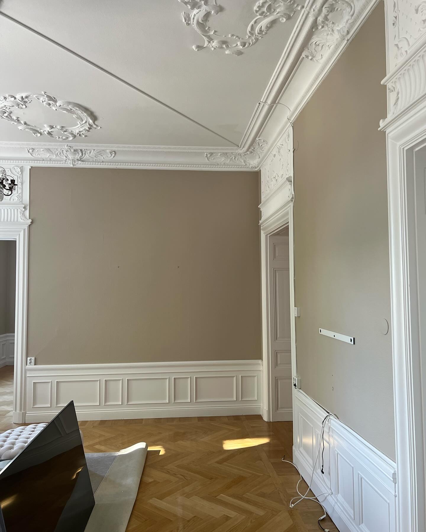 Rum med takstuckatur, beige väggar och vit bröstpanel