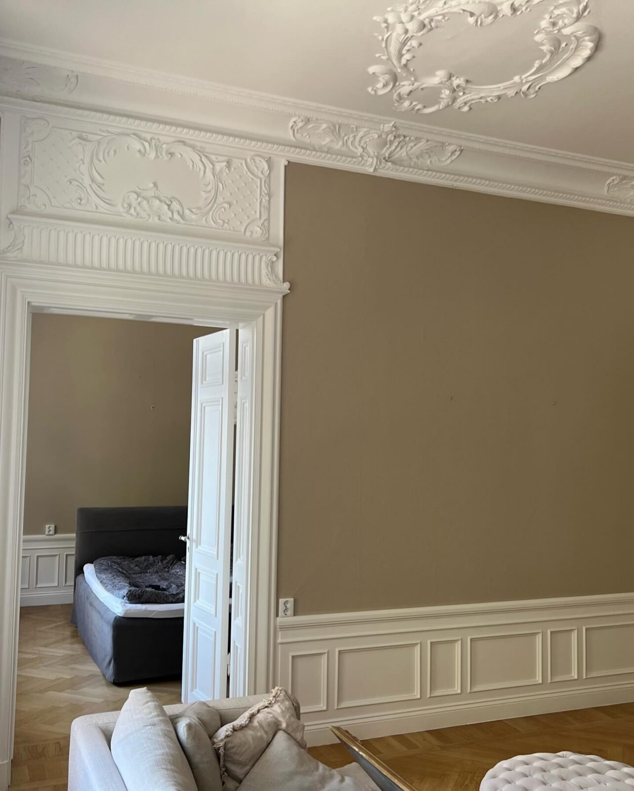 Stuckatur över dörr och beige vägg efter målning