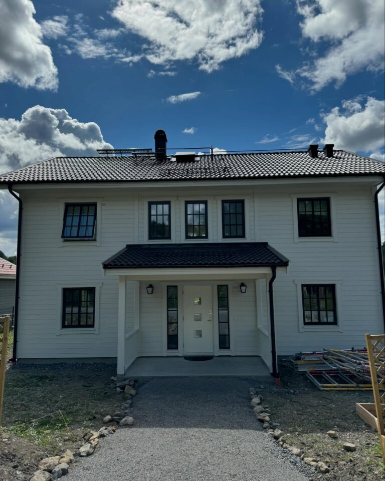 Nymålat vitt hus med svarta fönster, framsidan